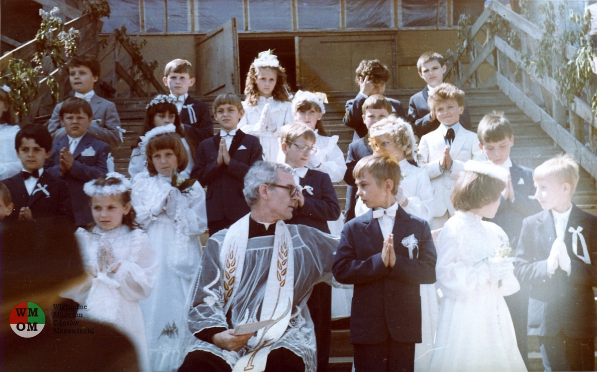 Proboszcz ks. Antoni Czulak z dziećmi komunijnymi na prowizorycznych drewnianych schodach do kościoła - 1985 rok, ze zbiorów Barbary Lang